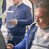 a man wearing headphones is sitting in the back seat of a car holding a piece of paper
