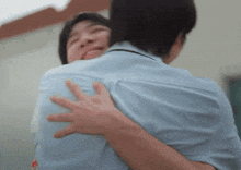 a man in a blue shirt is hugging a woman in a white shirt