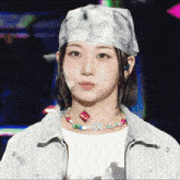 a woman wearing a head scarf and a necklace has a red circle on her face