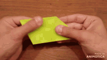 a person is holding a piece of green paper with the words made in animatica visible
