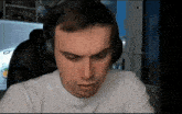 a man wearing headphones and a white shirt looks at the camera