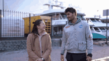 a man wearing a nasa jacket laughs with a woman
