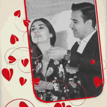 a black and white photo of a man putting a necklace on a woman surrounded by red hearts