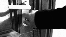 a black and white photo of a person opening a door with a key .