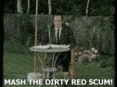 a man is sitting at a table with a microphone and the words mash the dirty red scum below him