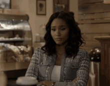 a woman sits at a table with her arms crossed and a cup of coffee in front of her