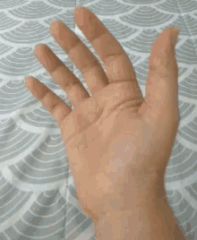 a close up of a person 's hand waving on a bed .