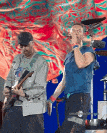 a man playing a guitar and another man singing on a stage