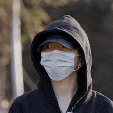 a person wearing a black hoodie and a white mask