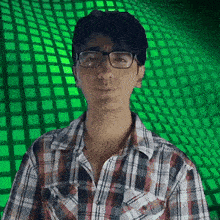 a man wearing glasses and a plaid shirt has a green background behind him