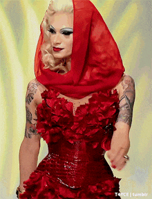 a woman in a red dress with a red scarf around her head has a tattoo on her arm