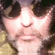 a close up of a man 's face wearing sunglasses and a beard