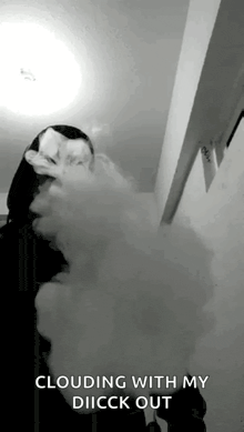 a black and white photo of a person smoking a cigarette and a cloud of smoke coming out of their mouth .