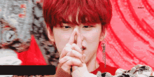 a young man with red hair is making a shhh gesture with his fingers