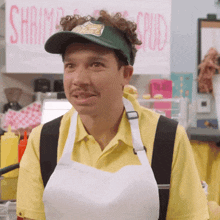 a man wearing a hat and apron is standing in front of a shrimp and squid sign