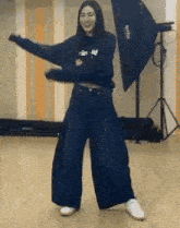 a woman is dancing in a room with a camera in the background .