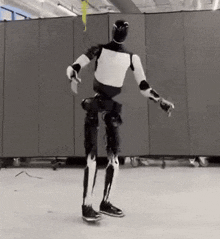 a black and white robot is standing on a skateboard in a room .