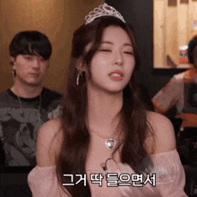 a woman wearing a pink off the shoulder top and a necklace with a heart on it