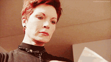 a woman with short red hair is looking at a piece of paper
