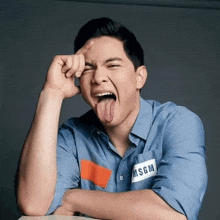 a man wearing a msgm shirt is sticking his tongue out and making a funny face .