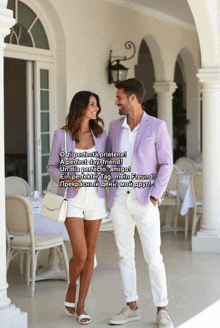 a man in a purple jacket and a woman in white shorts are standing next to each other in front of a restaurant
