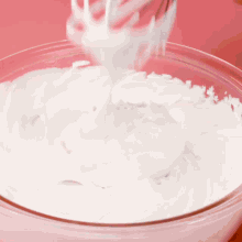 a person is whisking whipped cream in a glass bowl .