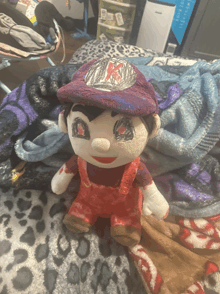 a stuffed mario doll is sitting on a leopard print blanket on a bed