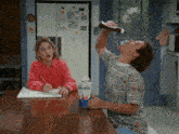 a man is drinking ketchup from a bottle while sitting at a table next to a carton of milk