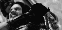 a black and white photo of a man in a mask holding another man 's neck .