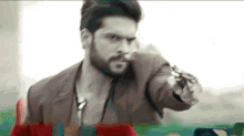 a man with a beard is holding a gun in his hand .