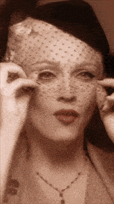 a woman wearing a veil and a hat looks at something