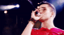 a man in a red shirt is singing into a microphone with the words rbd gif below him