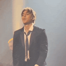a man in a suit and tie is standing on a stage with his eyes closed