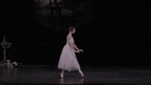 a ballerina in a white dress is dancing on a stage .