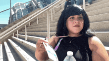a woman in a black tank top holds a bottle of water and a lanyard