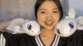 a girl holding two stuffed animals on her shoulders