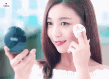 a woman is applying a powder to her face with a sns logo in the background
