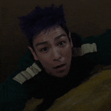 a man with purple hair is wearing a green sweater with nasa on the sleeve
