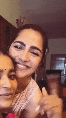 two women are posing for a picture together and smiling while giving a thumbs up .