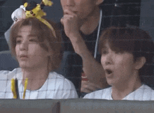 a couple of people are sitting in a stadium watching a baseball game .