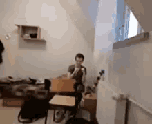 a man is sitting at a desk in a room with a chair .
