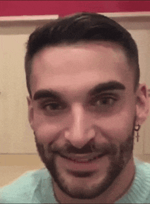 a man with a beard is smiling with a cross earring