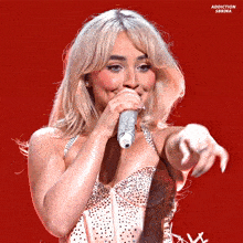 a woman singing into a microphone with addiction sabrina written on the bottom right