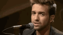 a man with a beard is singing into a microphone on a stage .