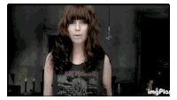 a woman wearing an iron maiden shirt is standing in a room .