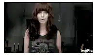 a woman wearing an iron maiden shirt is standing in a room .