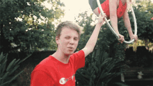 a man in a red shirt holds a hula hoop over a woman