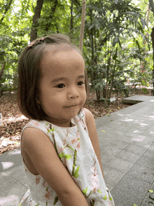 a little girl wearing a white dress with pink flowers on it