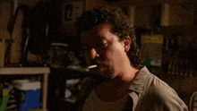 a man with curly hair and a beard smoking a cigarette