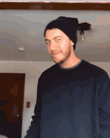 a man wearing a black beanie and a black sweater looks at the camera